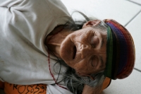 Una anciana duerme en el suelo de una tienda en la avenida central para escapar del calor de este medio día.